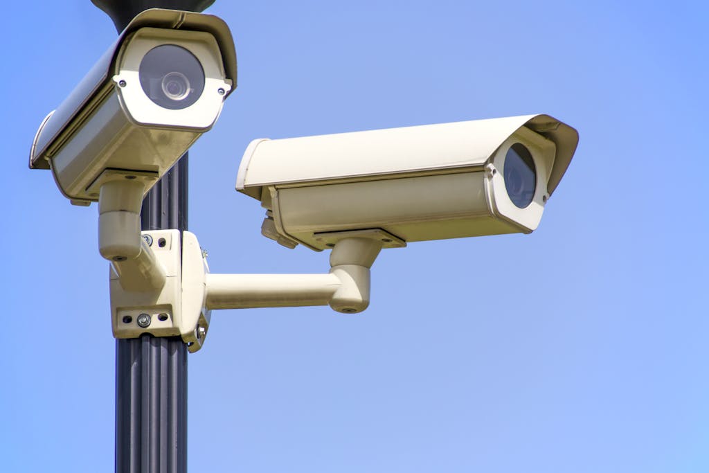 Outdoor security cameras mounted on a pole against a clear blue sky, ensuring vigilant surveillance.