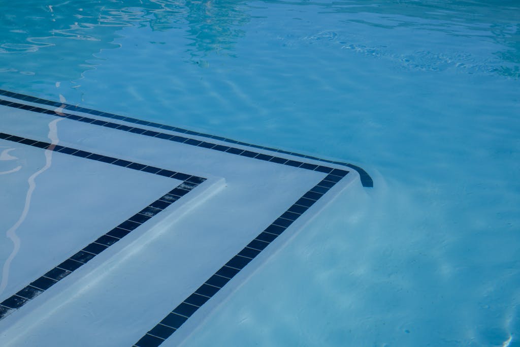 Serene view of a clear blue swimming pool with tiled steps and shimmering water.